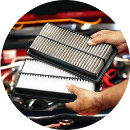 image of a person holding air filters, one dirty, one clean